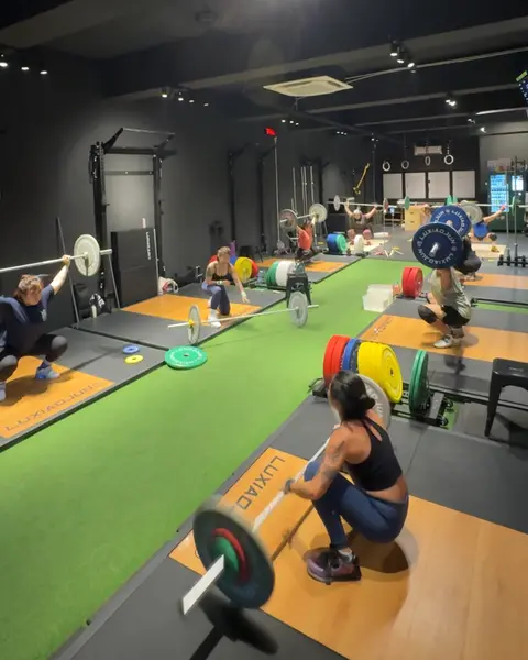 The weightlifting floor with several members training on separate platforms.